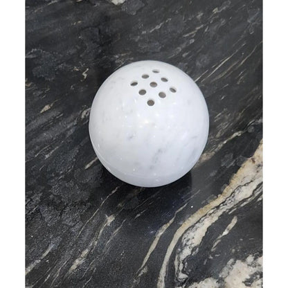 Carrara white marble sphere incense burner with natural veining on a black desk