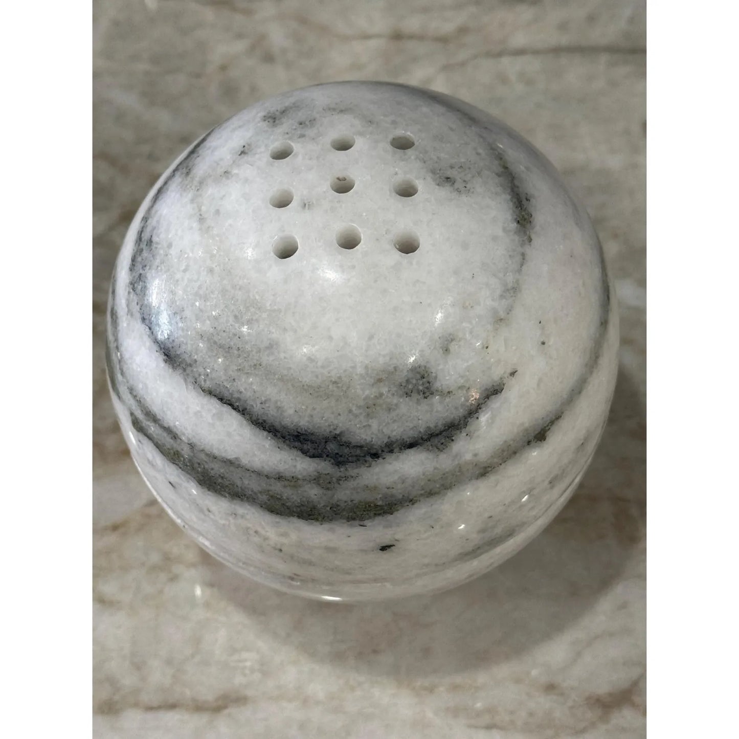 Wonderland white marble sphere incense burner with natural stone texture on a desk close up